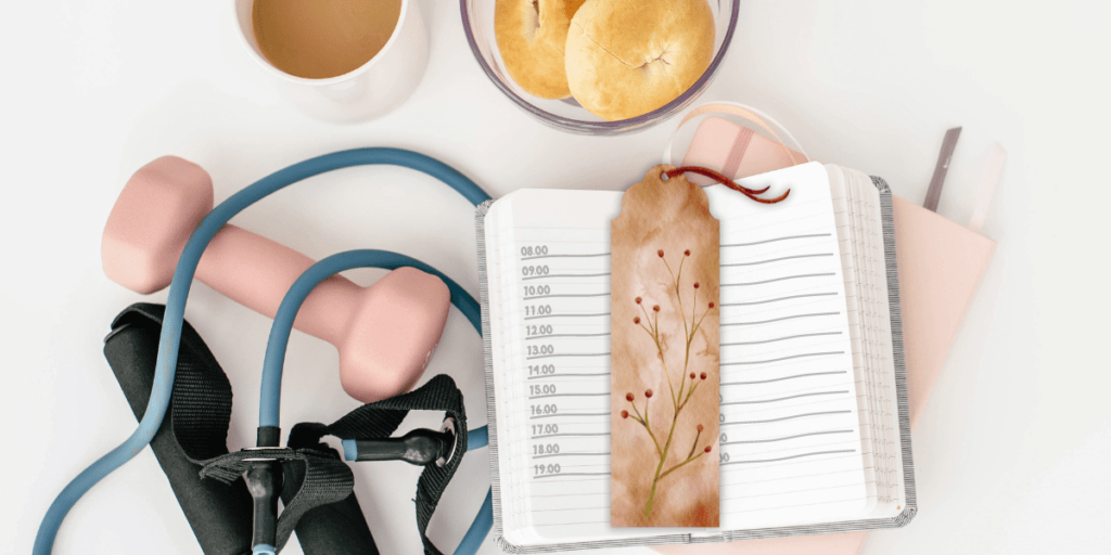 a planner with a bookmark , exercise equipment, and a drink.