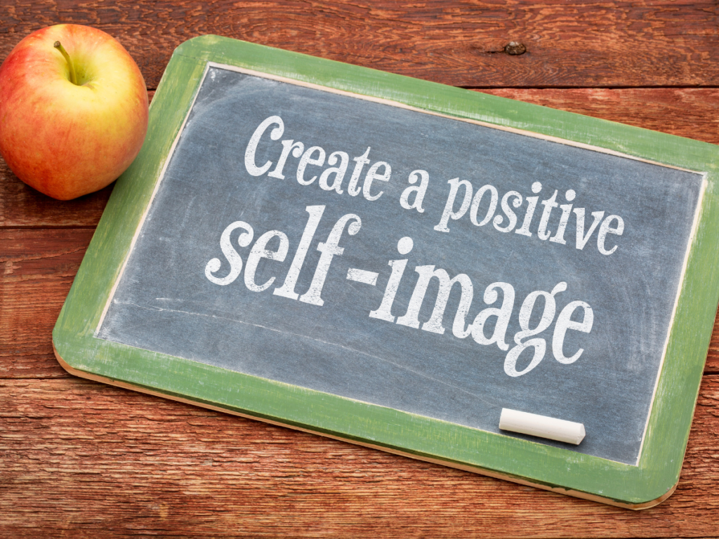 an apple beside a small chalkboard with the words "create a positive self image" written.